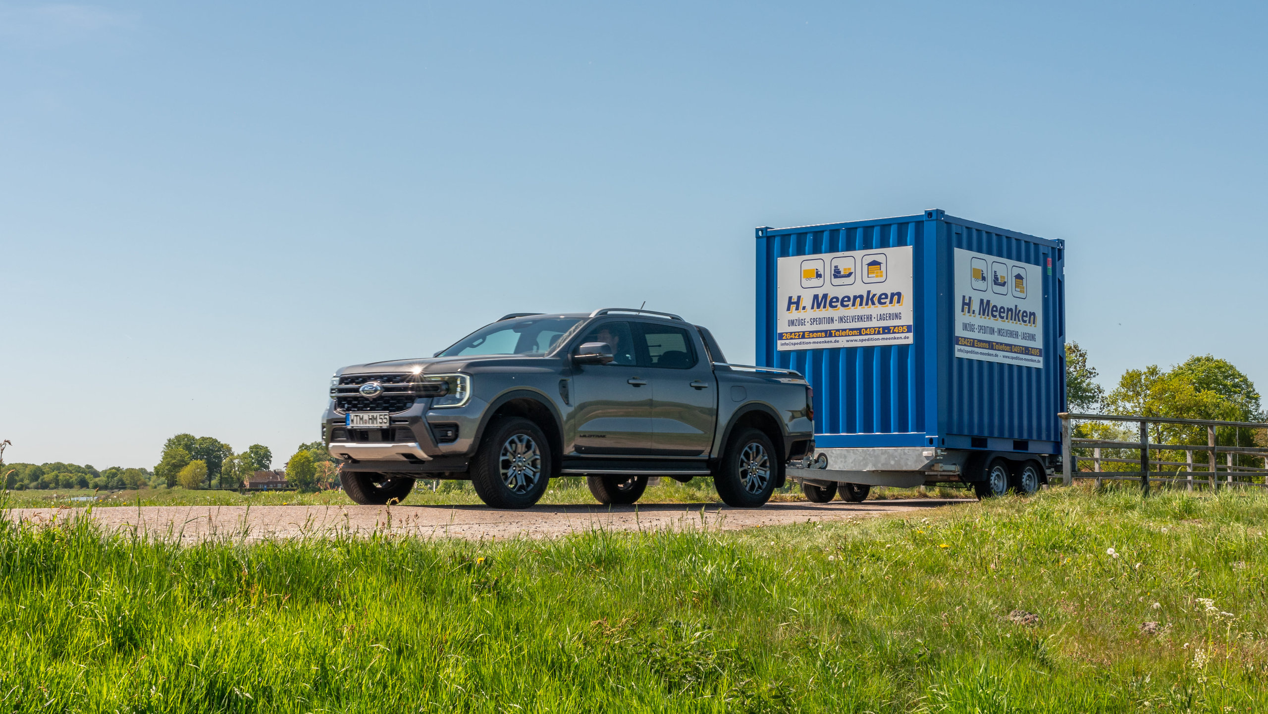 Pick-up der Spedition Container auf Anhänger fährt eine Landstraße entlang