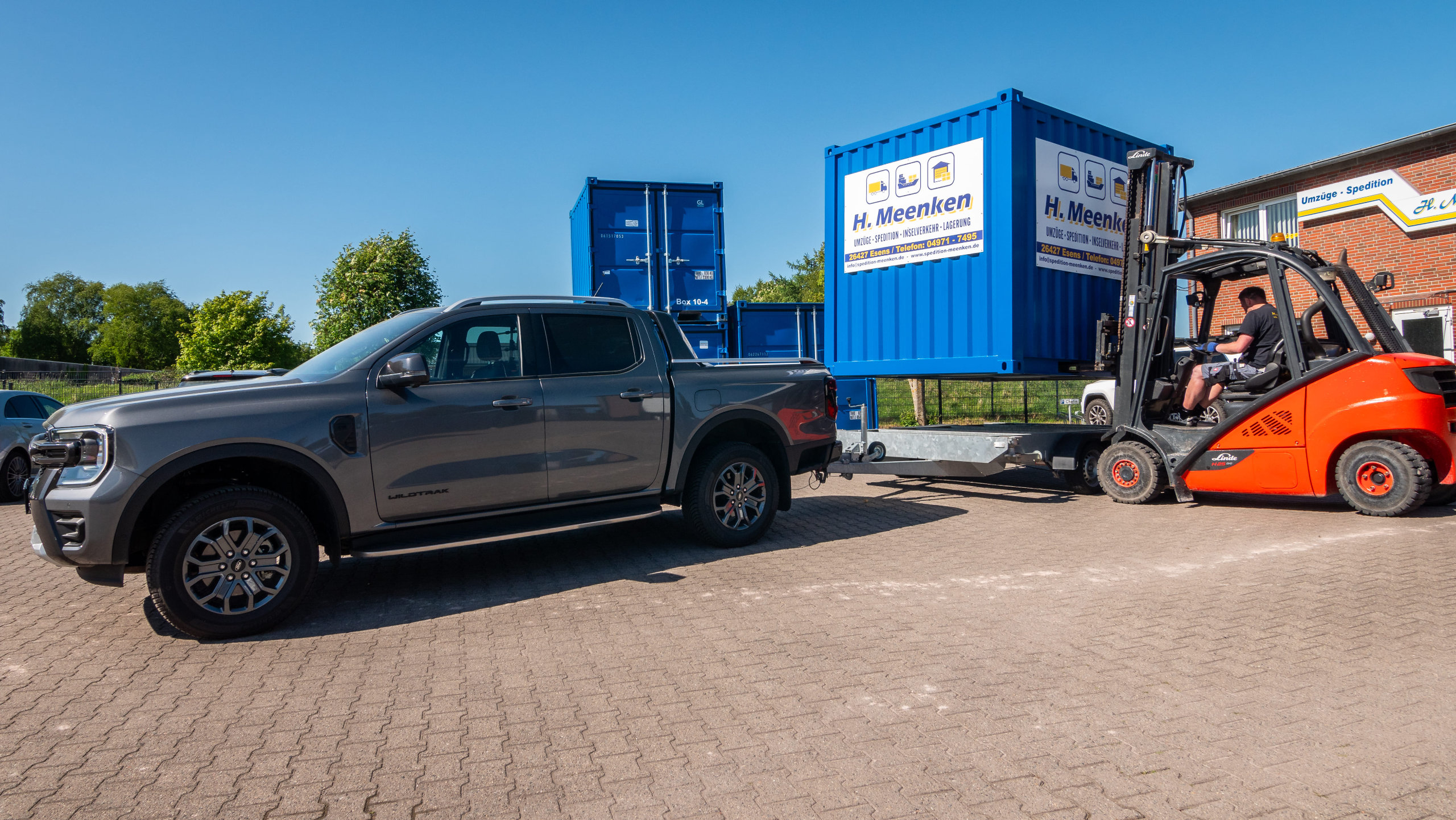 Pick-up der Spedition mit Anhänger wird von Gabelstapler mit Container beladen