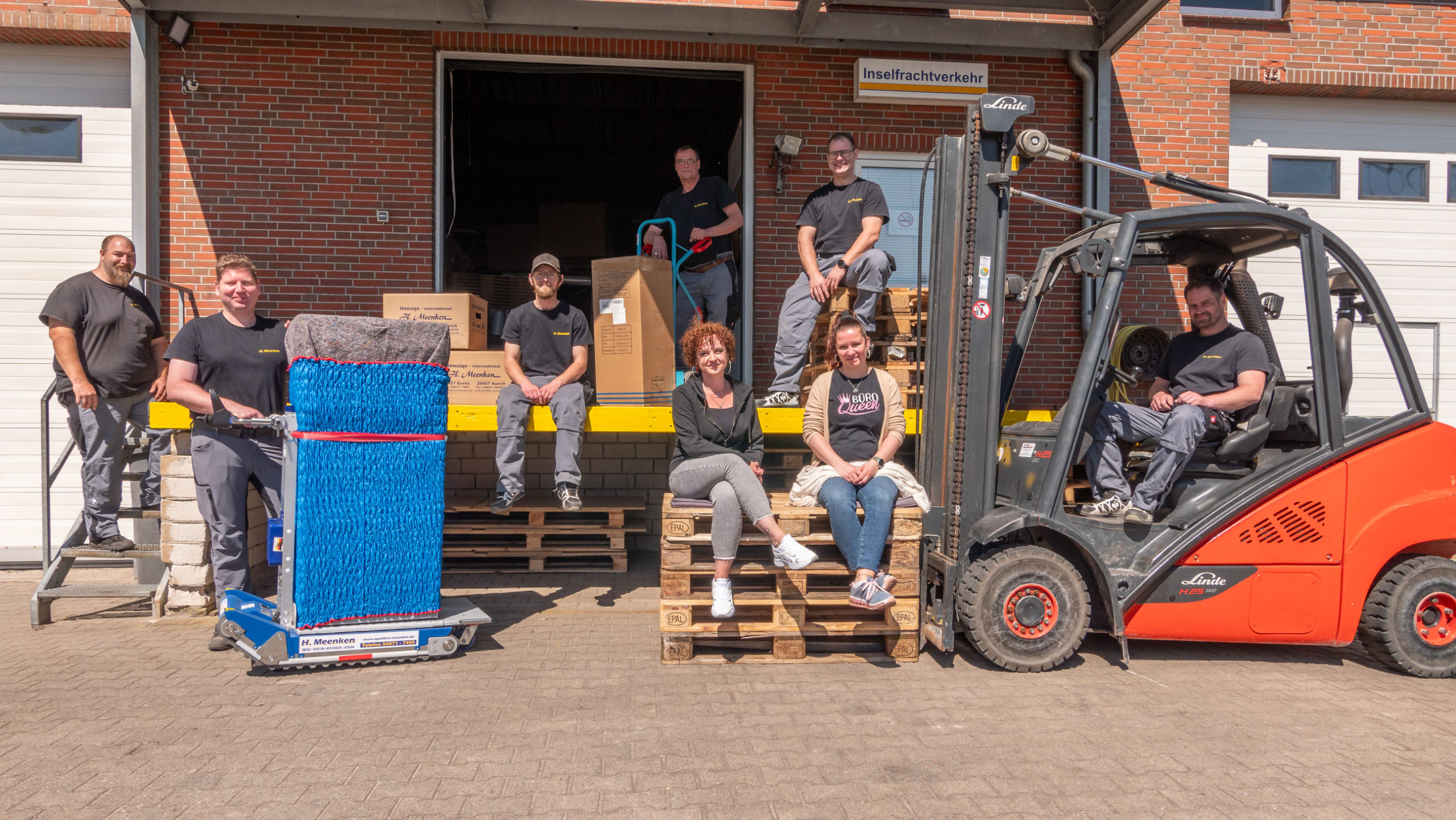 Teamfoto mit Gabelstapler vor der Laderampe der Lagerhalle